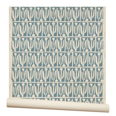 Partially unrolled wallpaper in an abstract tulip print in a repeating stripe on a dusty blue field.