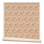 Partially unrolled wallpaper in an abstract tulip print in a repeating stripe on a rust field.