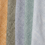 A row of folded linen swatches in mottled shades of blue, green, gray, brown and mustard.