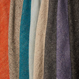 A row of folded linen-wool swatches in a variety of flecked colorways including tans, grays, reds and purples.