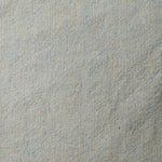 A swatch of blended linen-wool mix fabric in a flecked cream color with blue overtones.