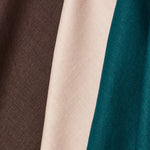 A group of three folded pieces of linen fabric in shades of espresso, turquoise and pale pink.