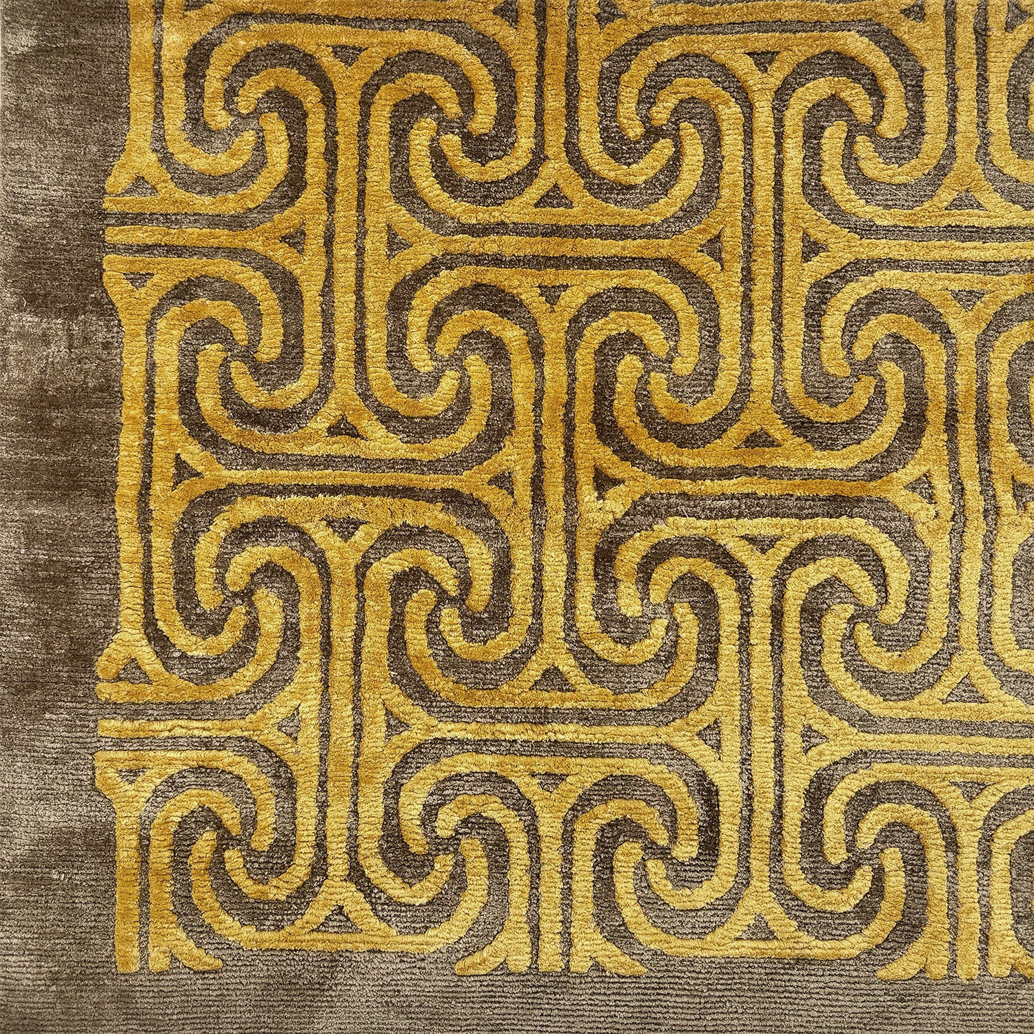 Detail of a handkotted rug in a classic greek key pattern in yellow on a brown field