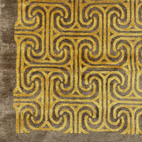 Detail of a handkotted rug in a classic greek key pattern in yellow on a brown field