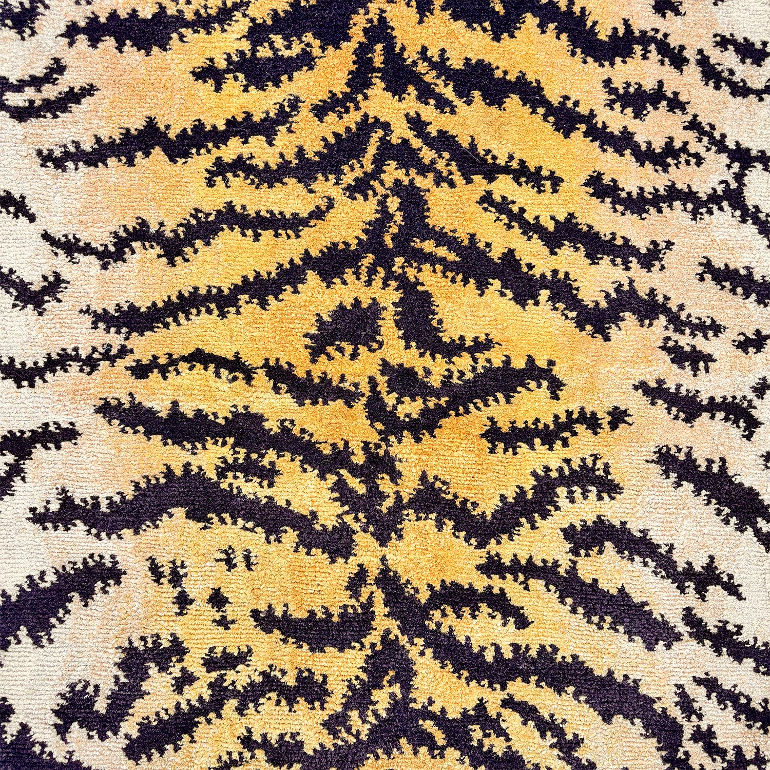 Detail of a wool rug with a large tiger skin pattern in black, white and orange. 