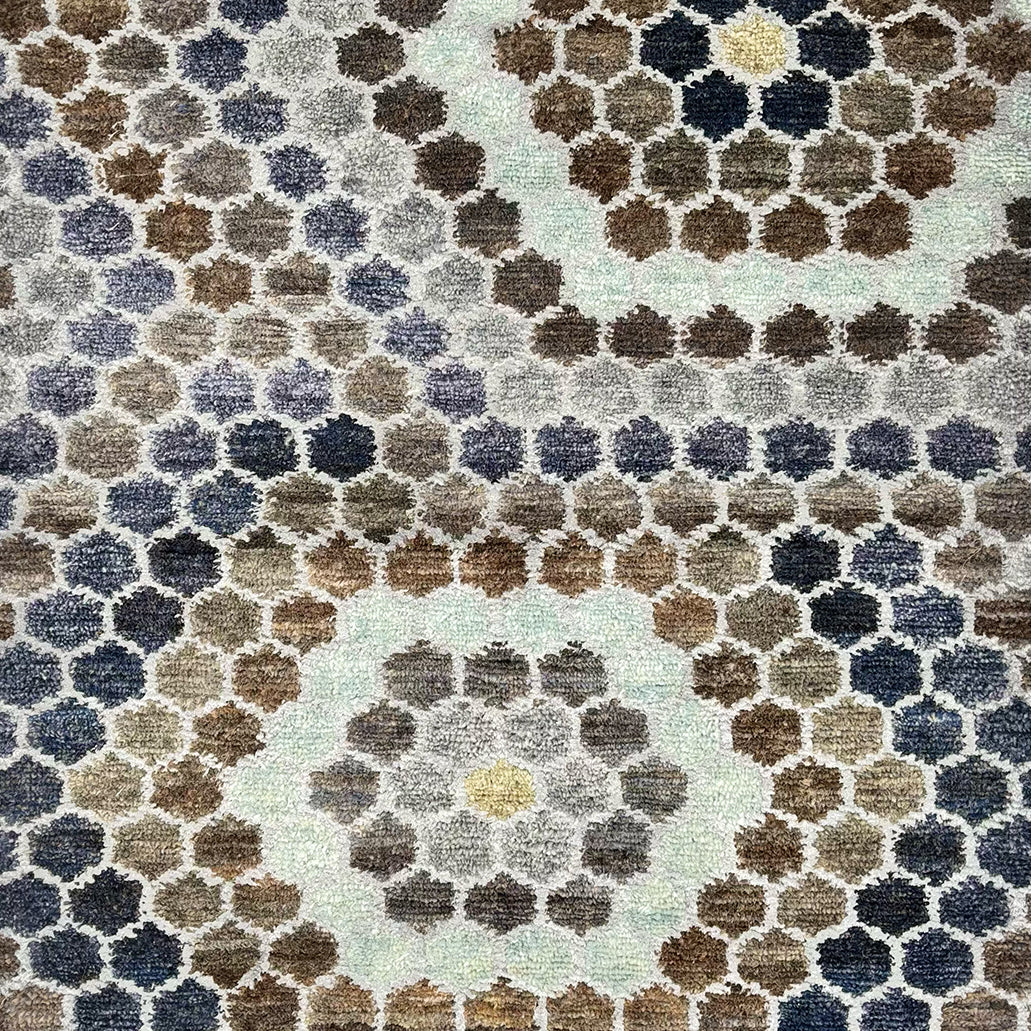 Detail of a handknotted rug with a classic hexagon pattern in shades of blue, grey, white and indigo. 