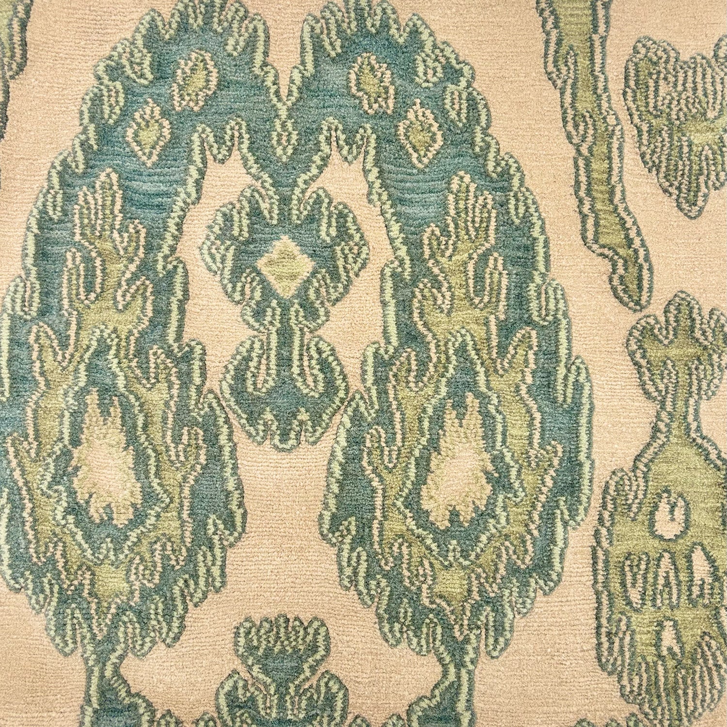 Detail of a silk rug with an ikat inpsired pattern in blue and breen on an ivory field
