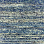 Detail of a wool rug with a textural strié stripe pattern in indigo and cream