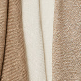 A group of three draped open-weave interior fabric swatches in tan, beige and cream.