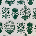 Detail of wallpaper in a repeating vase and plant print in green on a white field.