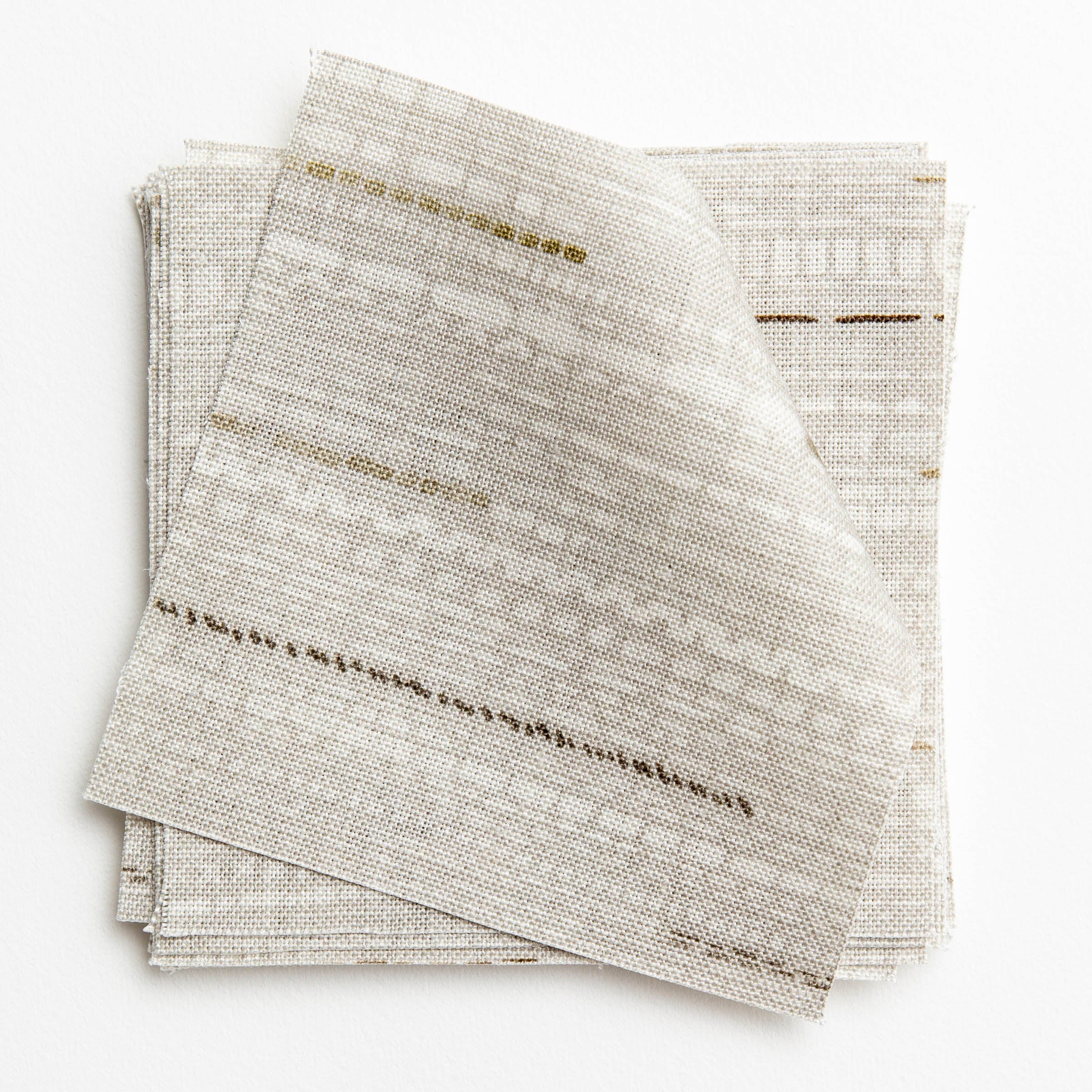 A stack of fabric swatches in a textural striped pattern in shades of gray, cream and tan.