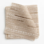 A stack of fabric swatches in a textural striped pattern in shades of cream and tan.