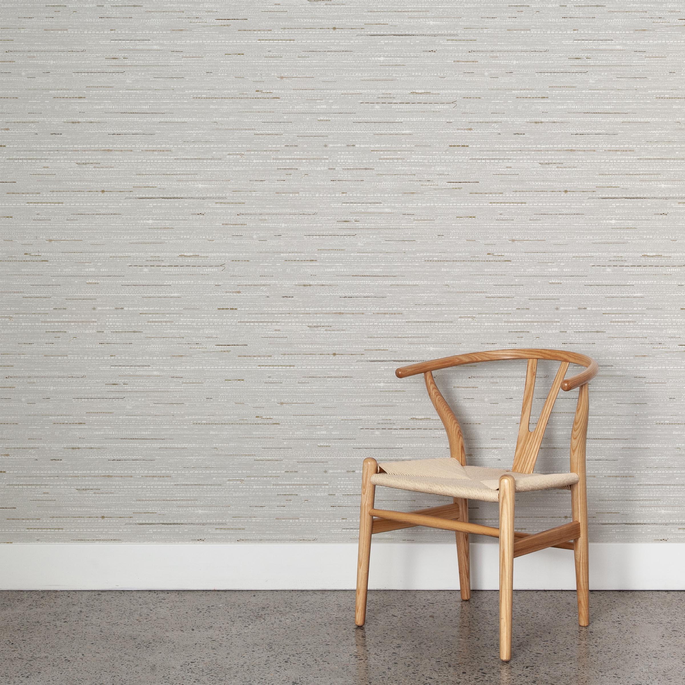 A wooden chair stands in front of a wall papered in a textural striped pattern in shades of gray, white and tan.