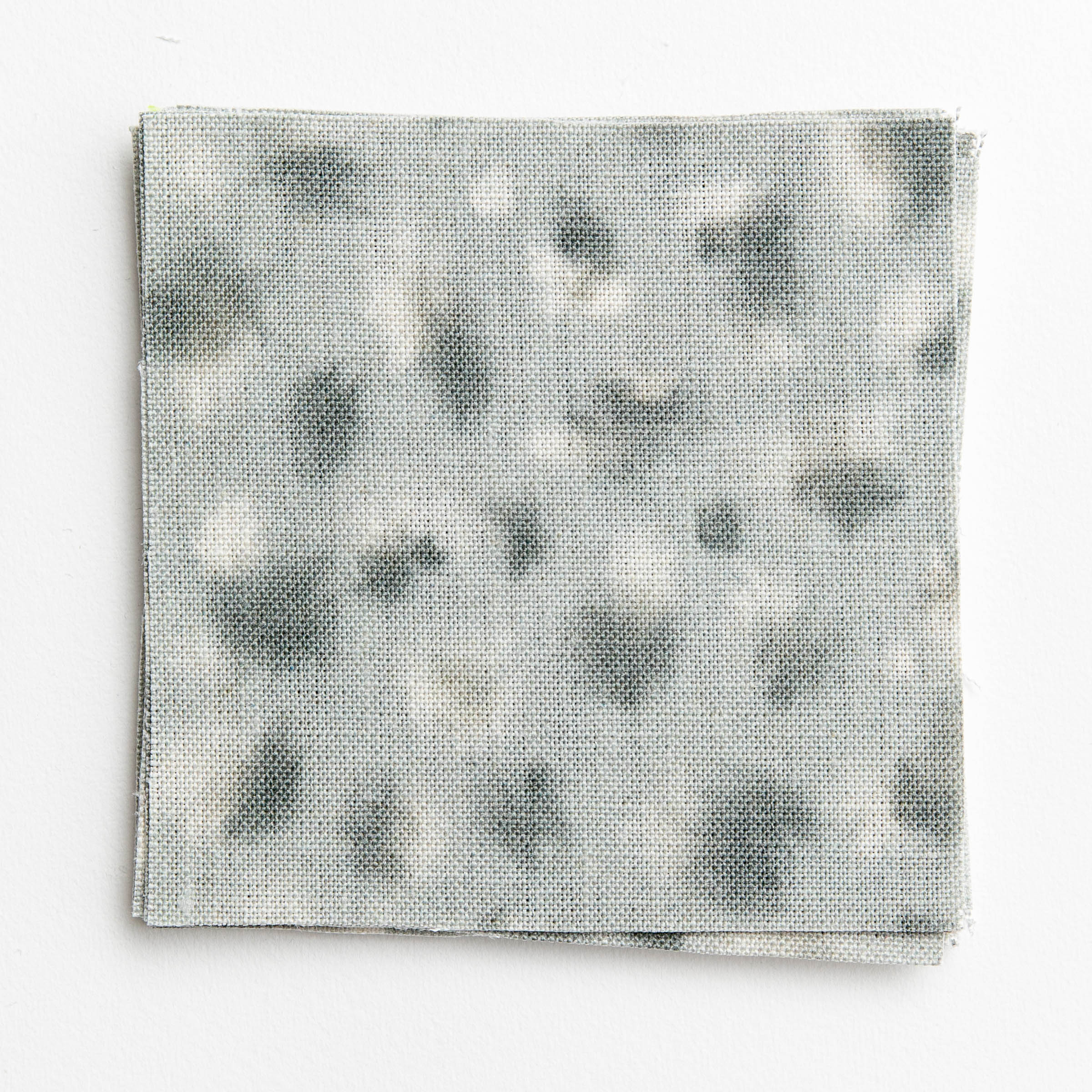 A stack of fabric swatches in a painterly animal print in cream and blue on a light blue field.