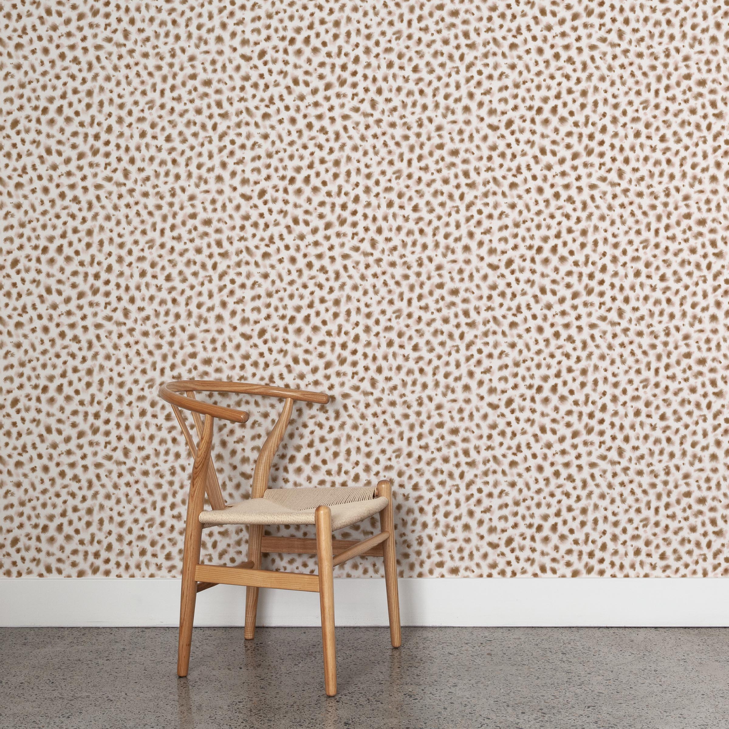 A wooden chair stands in front of a wall papered in a painterly animal print in cream and brown on a white field.