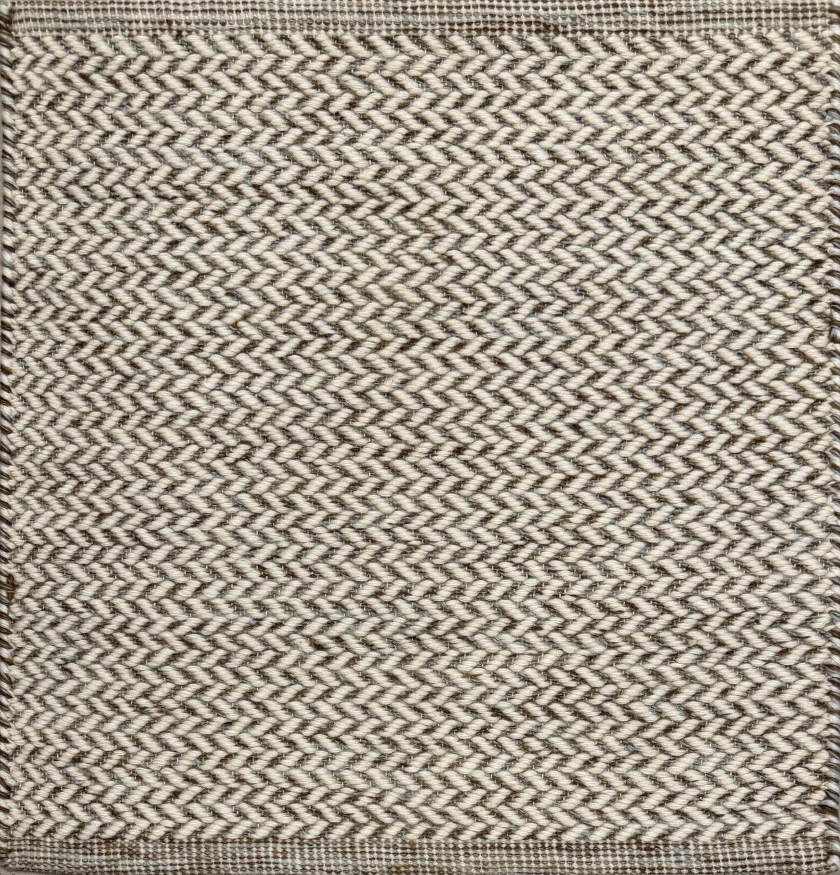Textured rug with a herringbone pattern in white and brown.