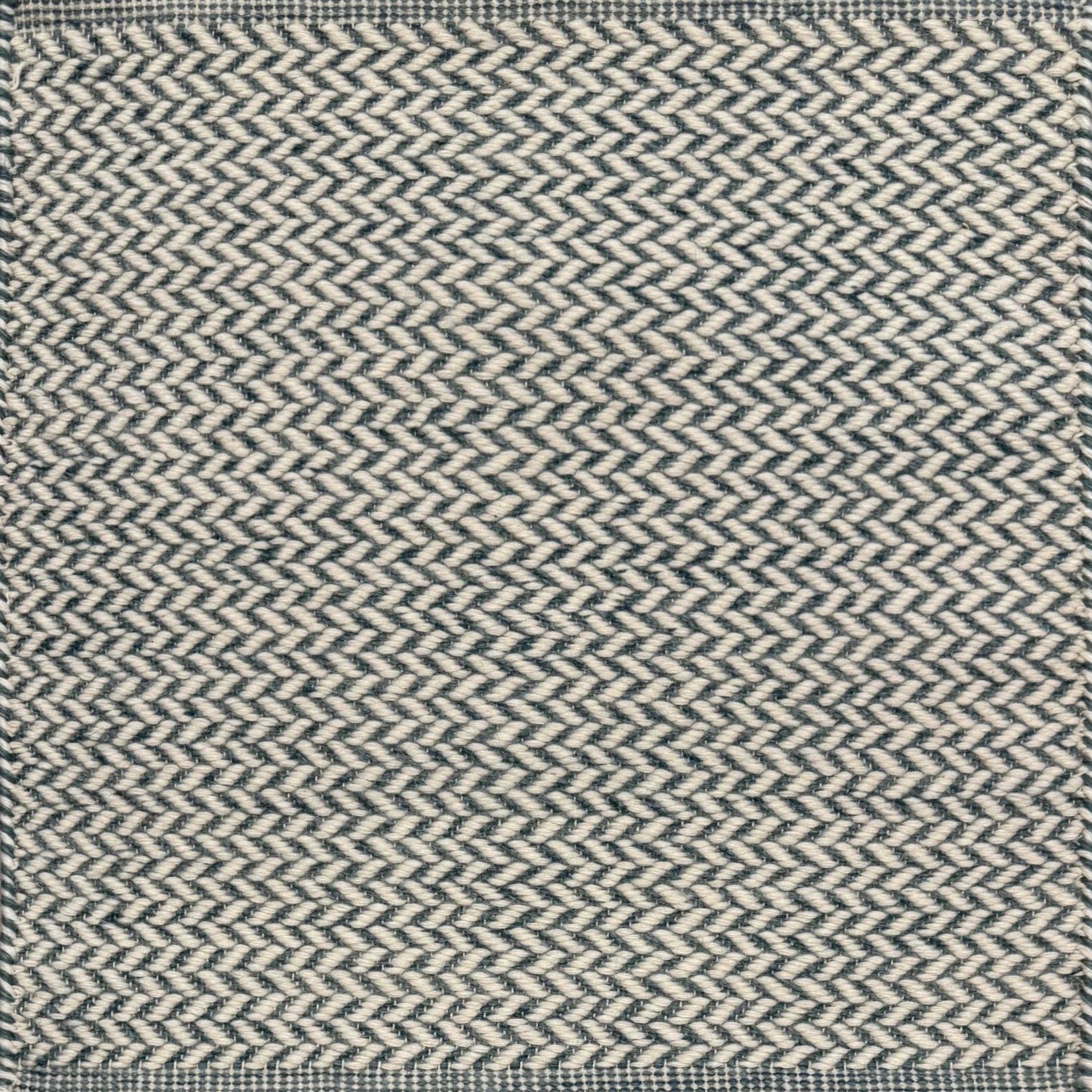 Textured rug with a herringbone pattern in white and teal.