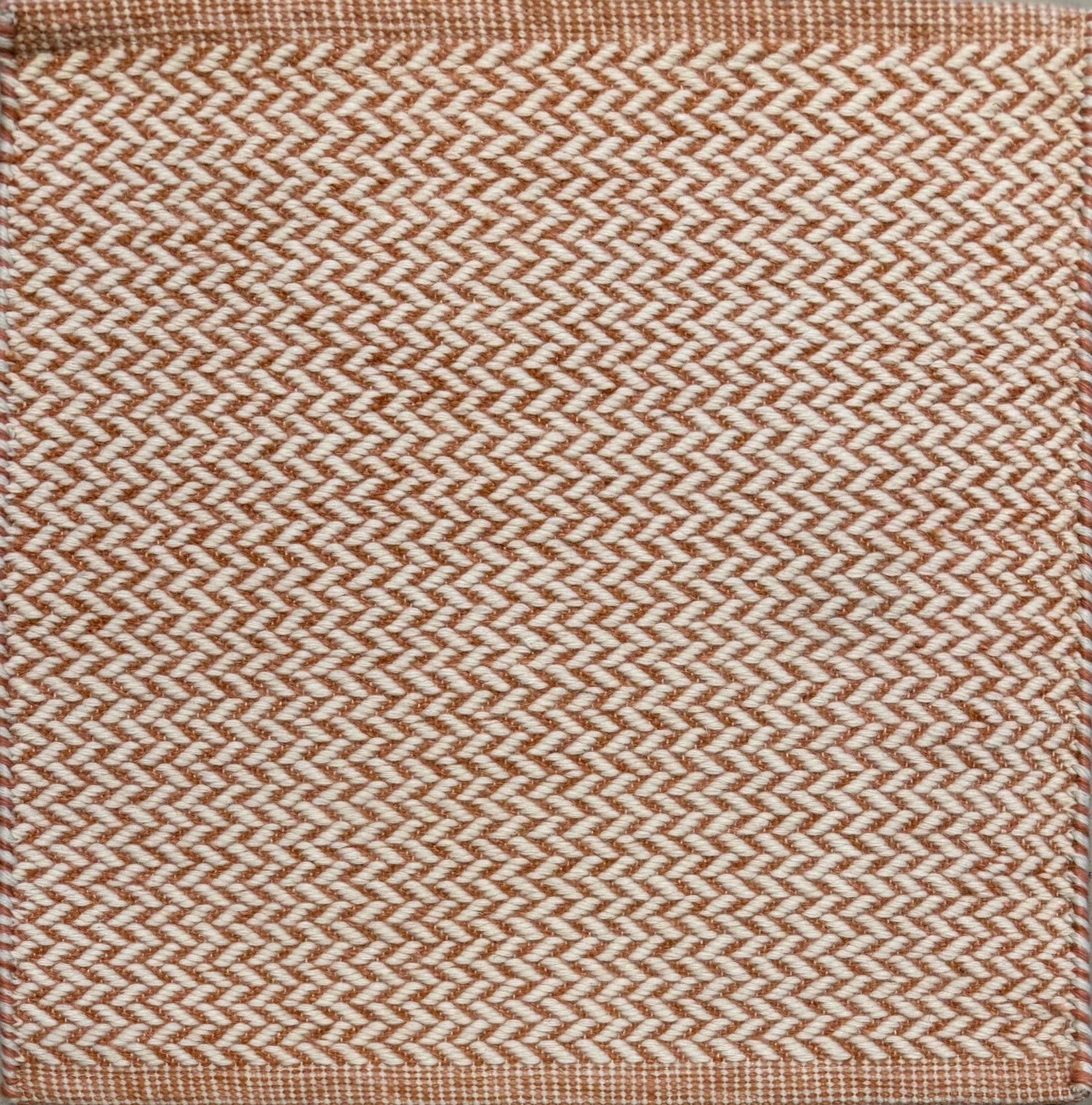 Textured rug with a herringbone pattern in white and orange.