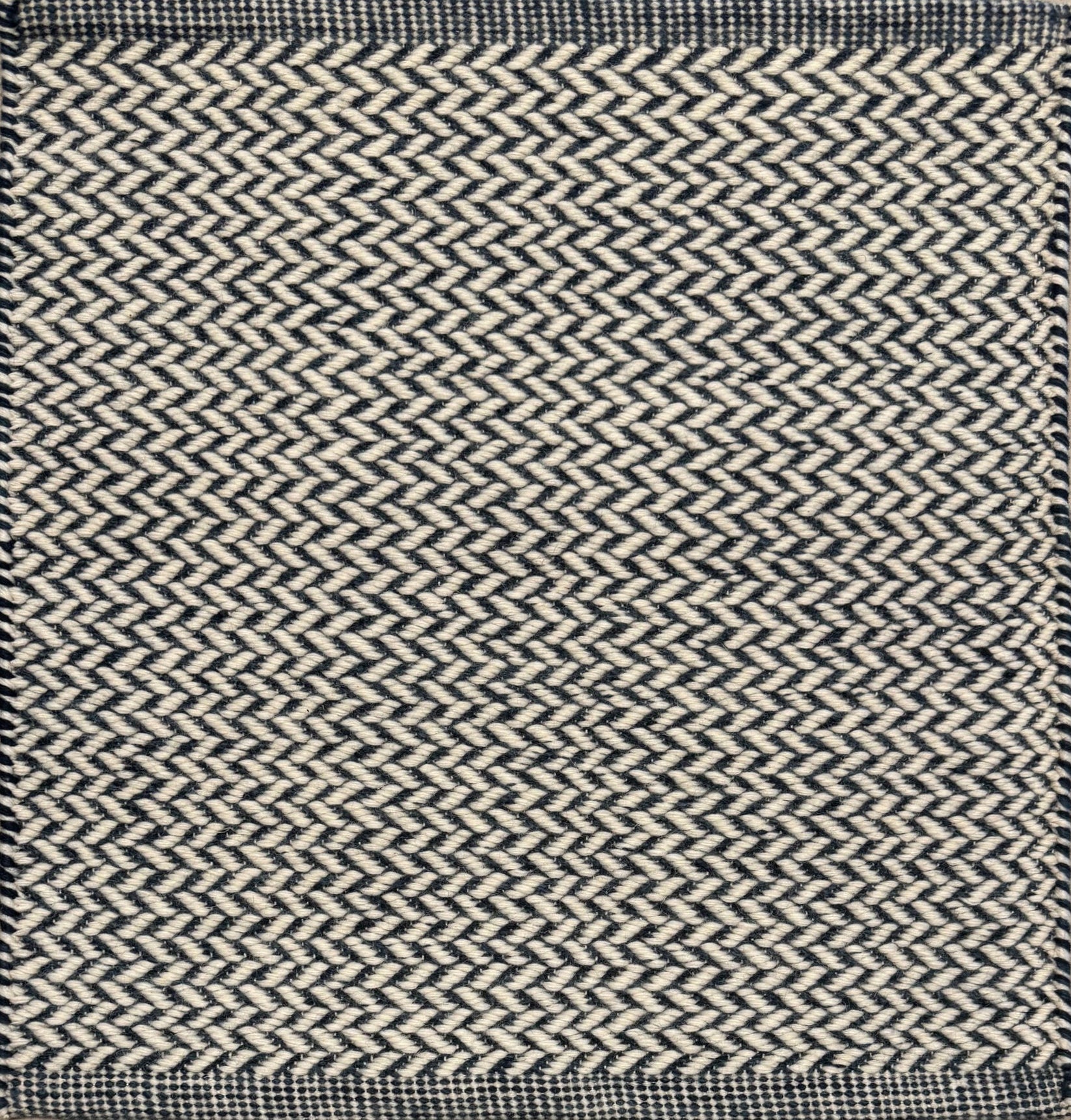 Textured rug with a herringbone pattern in white and navy blue