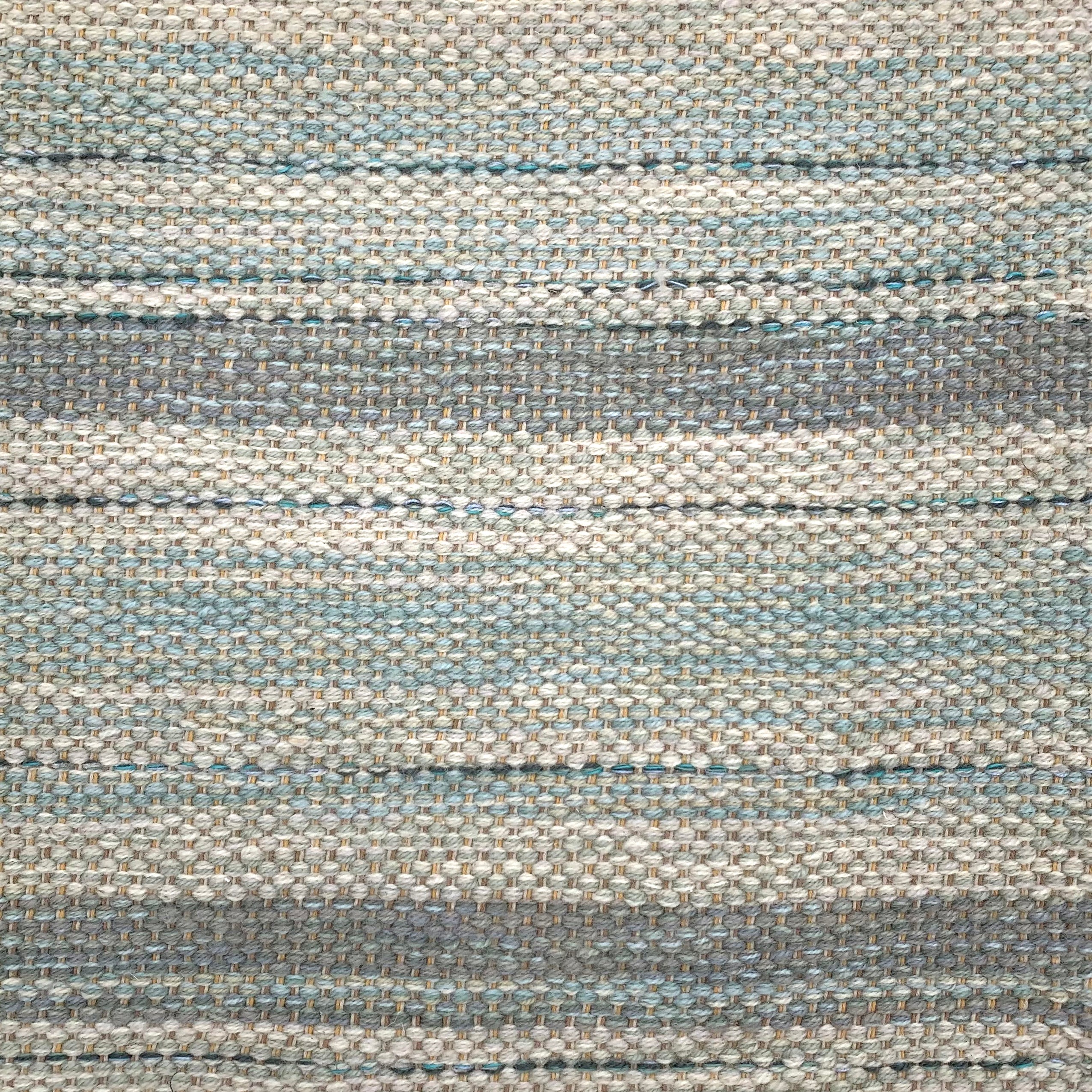 Handwoven rug detail in a stripe design in blue and grey 