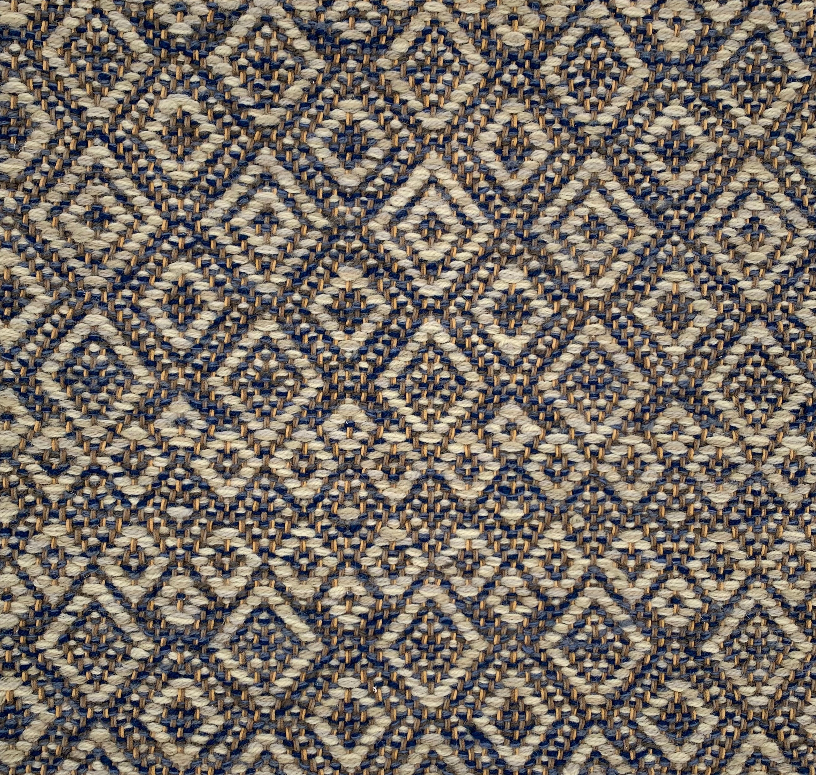 Handwoven rug detail in a diamond design in blue, cream and yellow