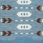 Handwoven rug detail in a Swedish arrow design in brown and white on a green field. 