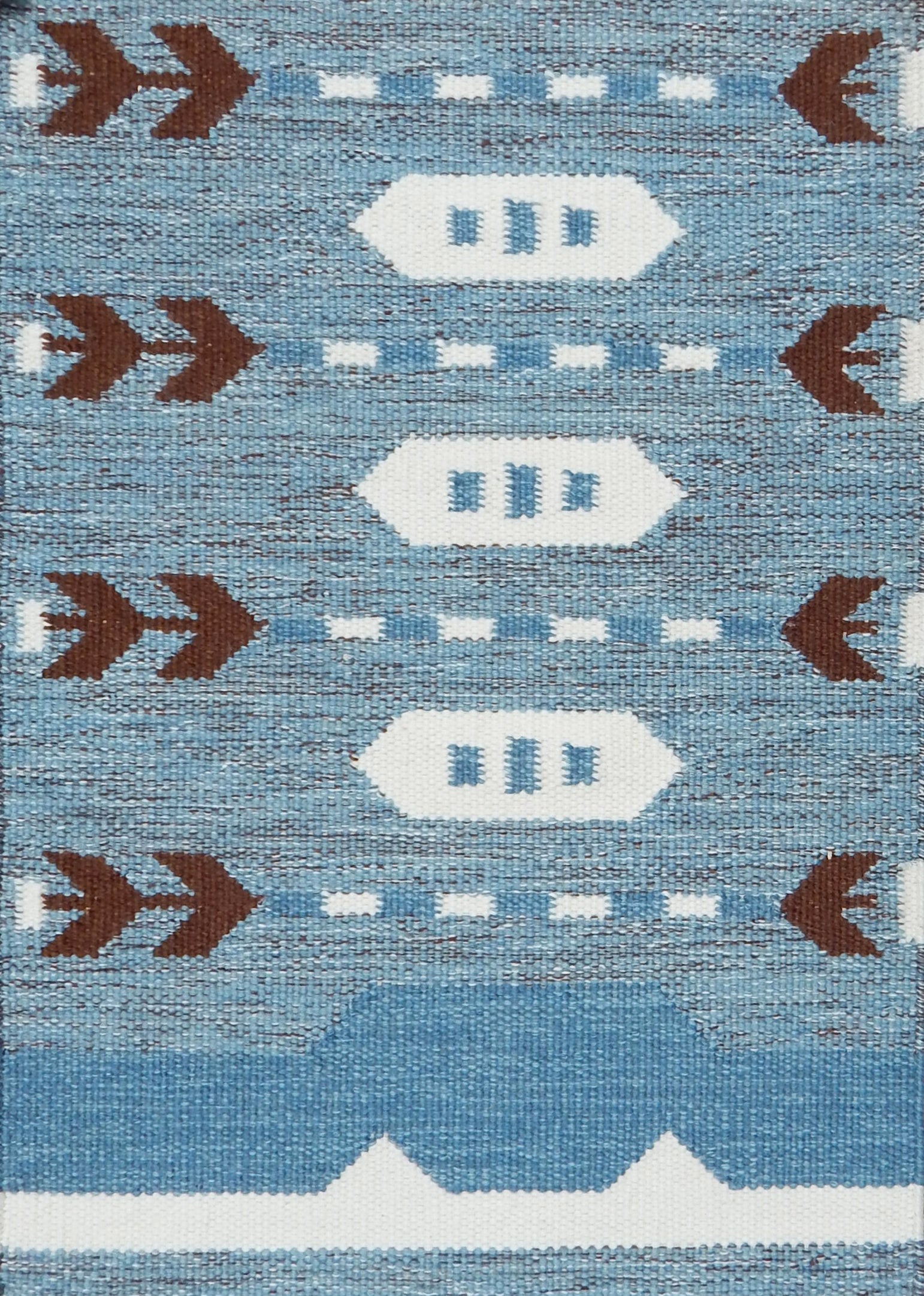 Handwoven rug detail in a Swedish arrow design in brown and white on a green field. 