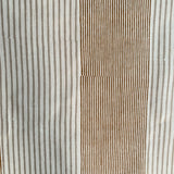 Detail of fabric in an irregular stripe print in rust and tan on a white field.