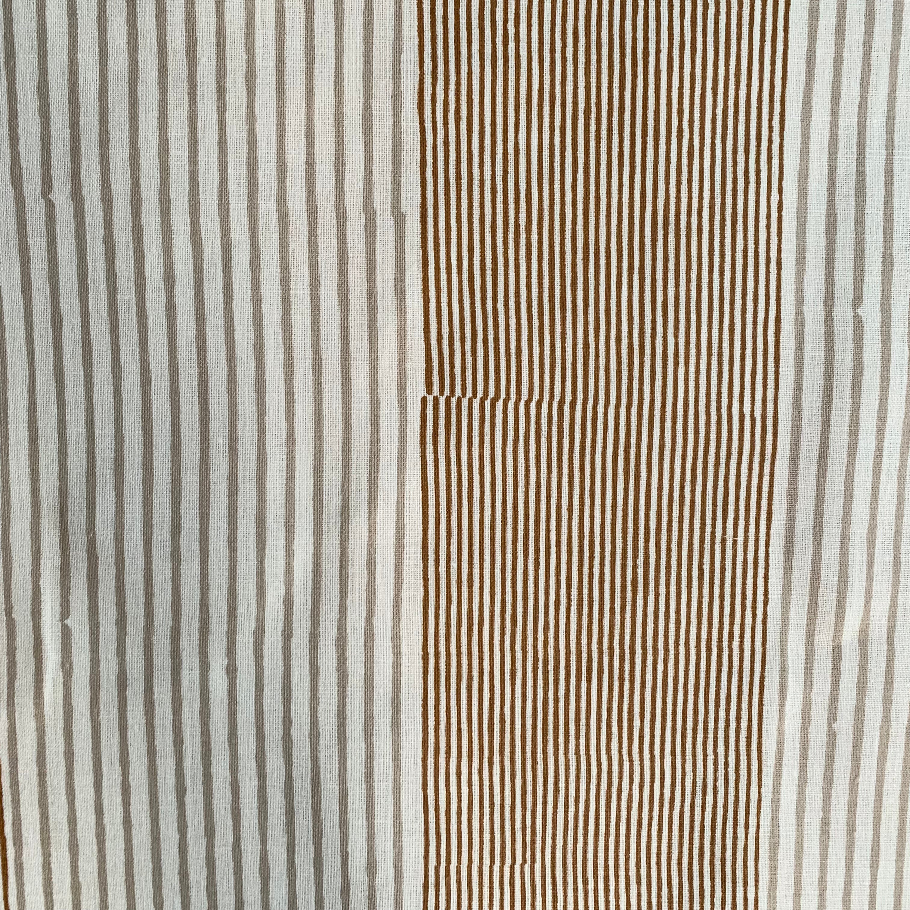 Detail of fabric in an irregular stripe print in rust and tan on a white field.