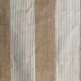 Detail of fabric in an irregular stripe print in rust and tan on a white field.