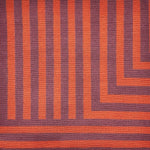 Detail of a handknotted rug in a graphic geometric design in red and eggplant purple.