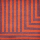 Detail of a handknotted rug in a graphic geometric design in red and eggplant purple.