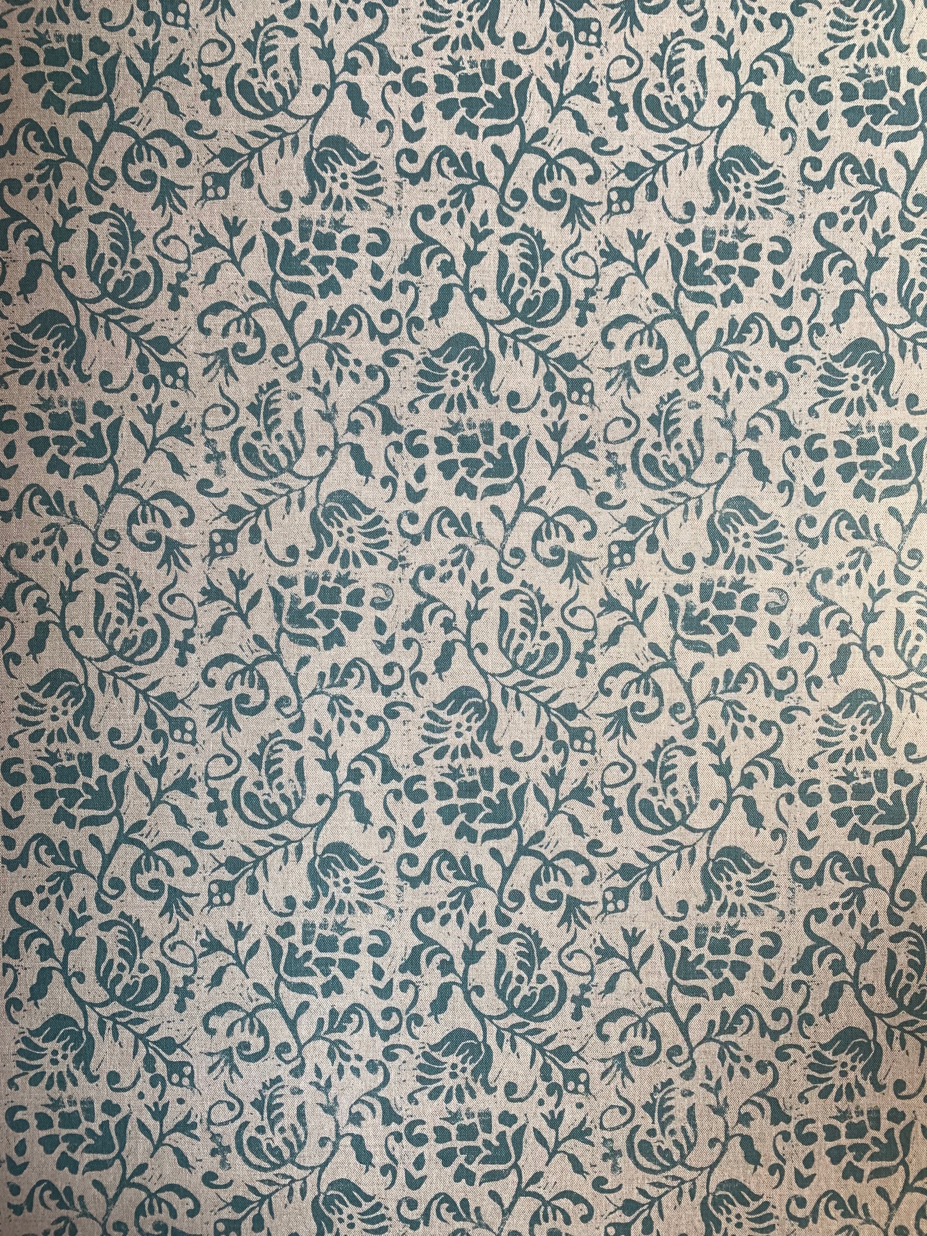 Detail of fabric in a botanical print in blue on a light brown field.