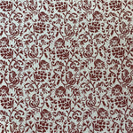 Detail of fabric in a botanical print in red on a cream field.