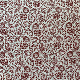 Detail of fabric in a botanical print in red on a cream field.