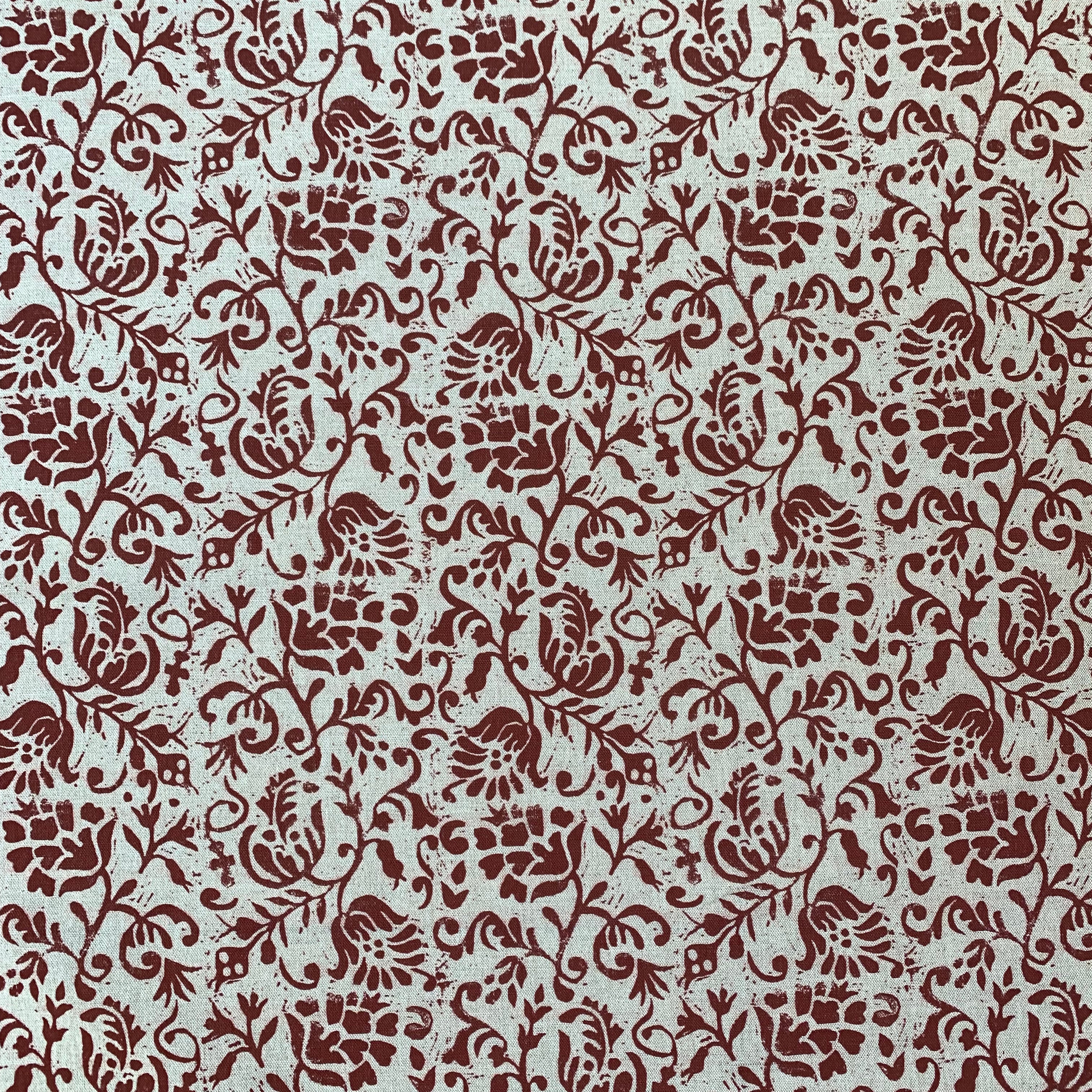 Detail of fabric in a botanical print in red on a cream field.