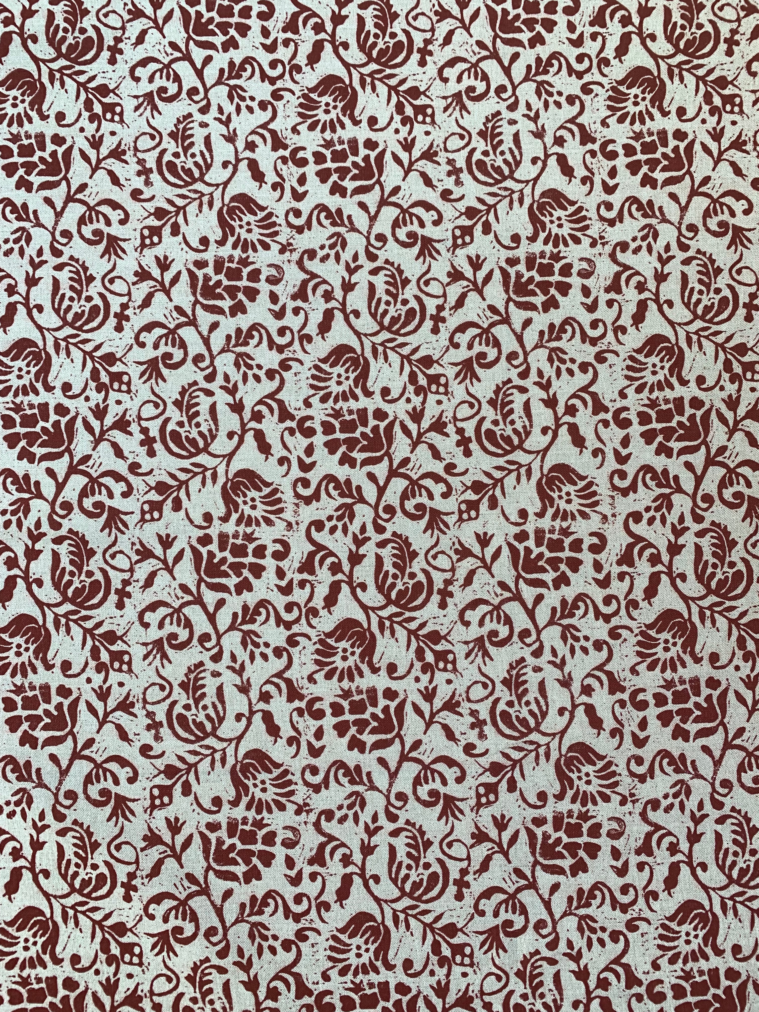 Detail of fabric in a botanical print in red on a cream field.