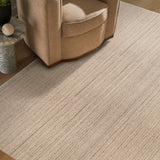 Beige armchair next to a textured beige rug on a wooden floor.