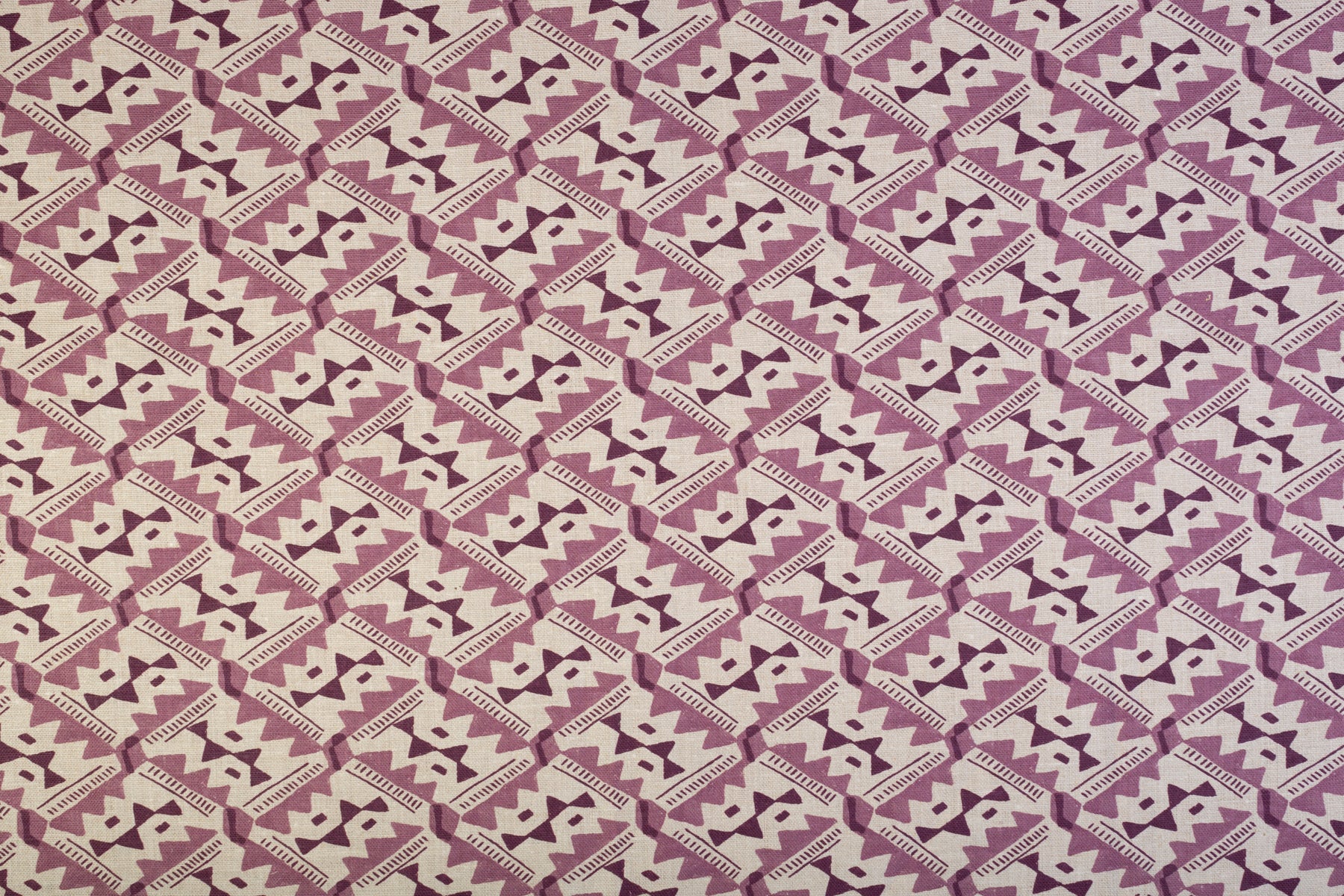 Detail of fabric in painterly diamond print in shades of purple on a white field.