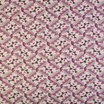 Detail of fabric in painterly diamond print in shades of purple on a white field.