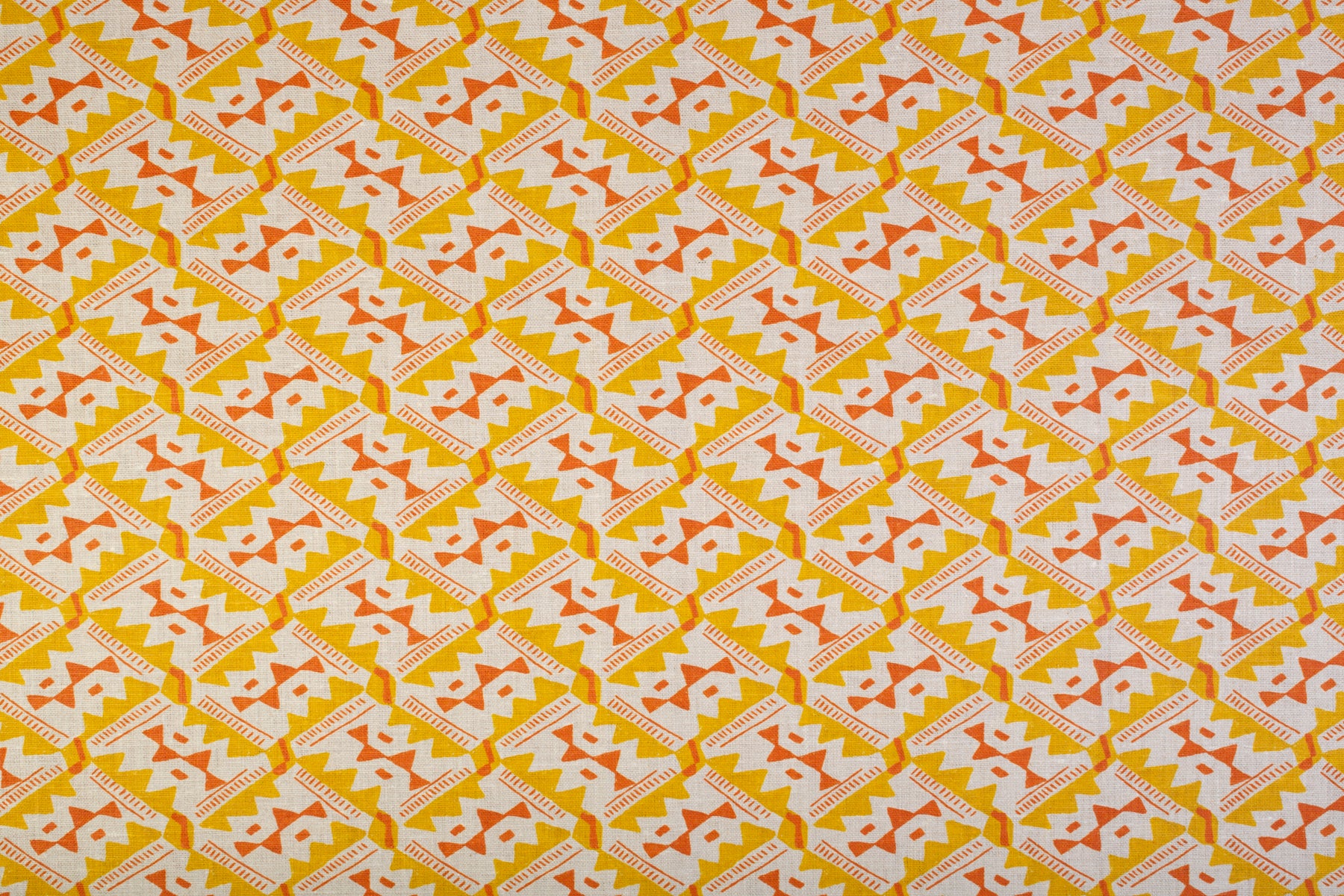 Detail of fabric in painterly diamond print in yellow and orange on a white field.