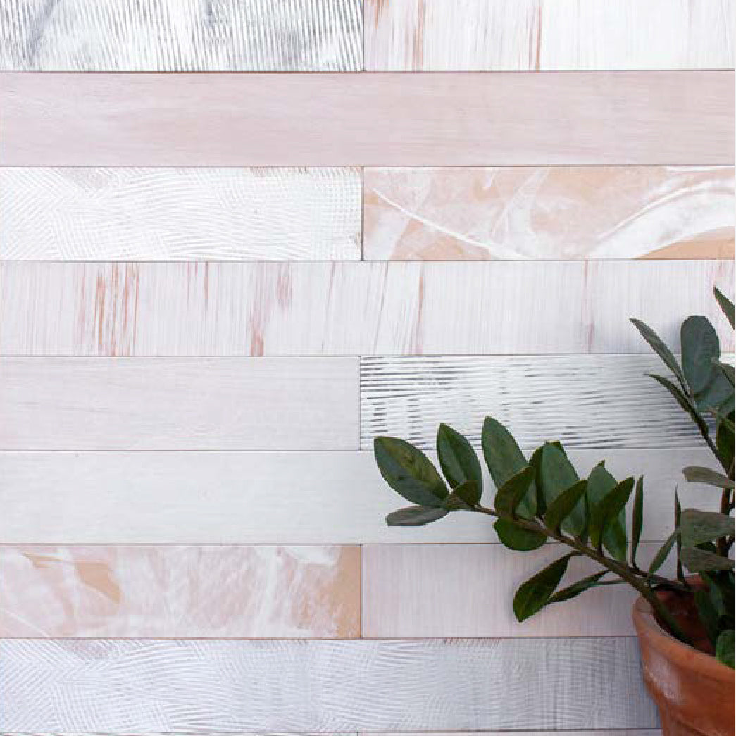 A plant stands in front of a wall papered in textured leather wall tiles in light pink.