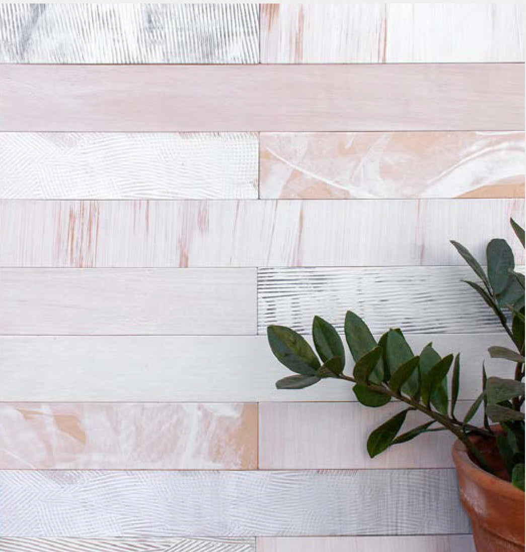 A plant stands in front of a wall papered in textured leather wall tiles in light pink.