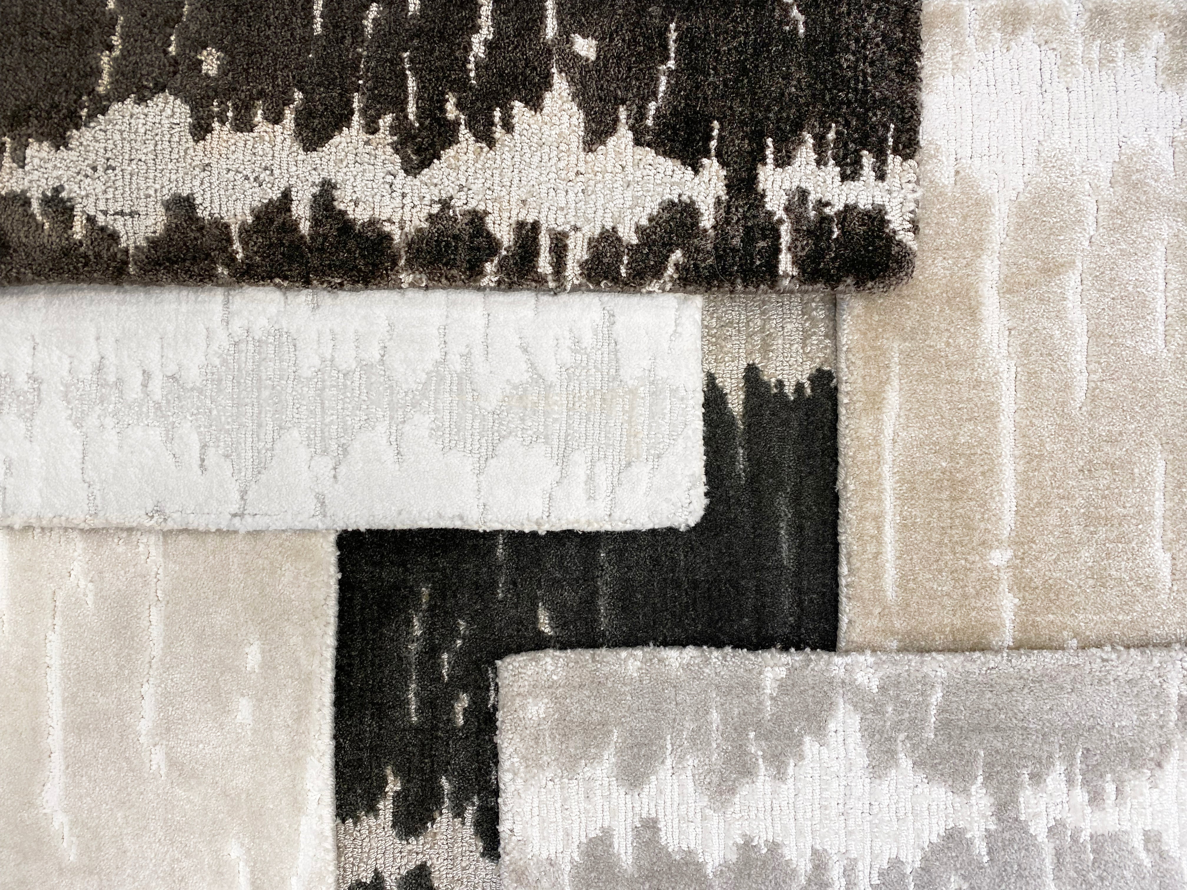 Stacked broadloom carpet samples in a contemporary abstract design in neutral colors. 