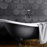 A clawfoot tub stands in front of a wall covered in leather tiles in a scallop pattern in gray.