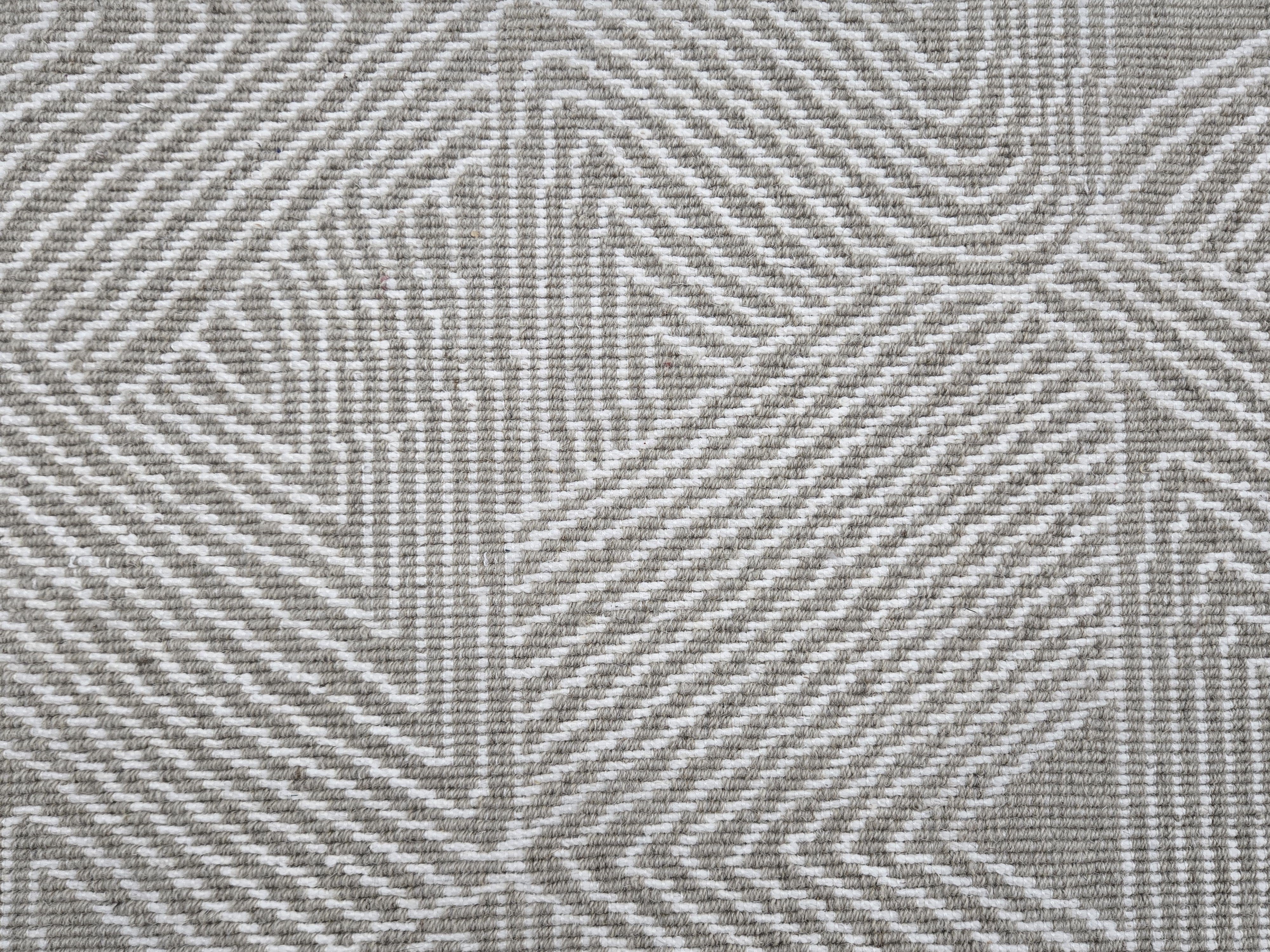 Broadloom carpet sample in a geometric linear pattern in cream on a taupe field. 