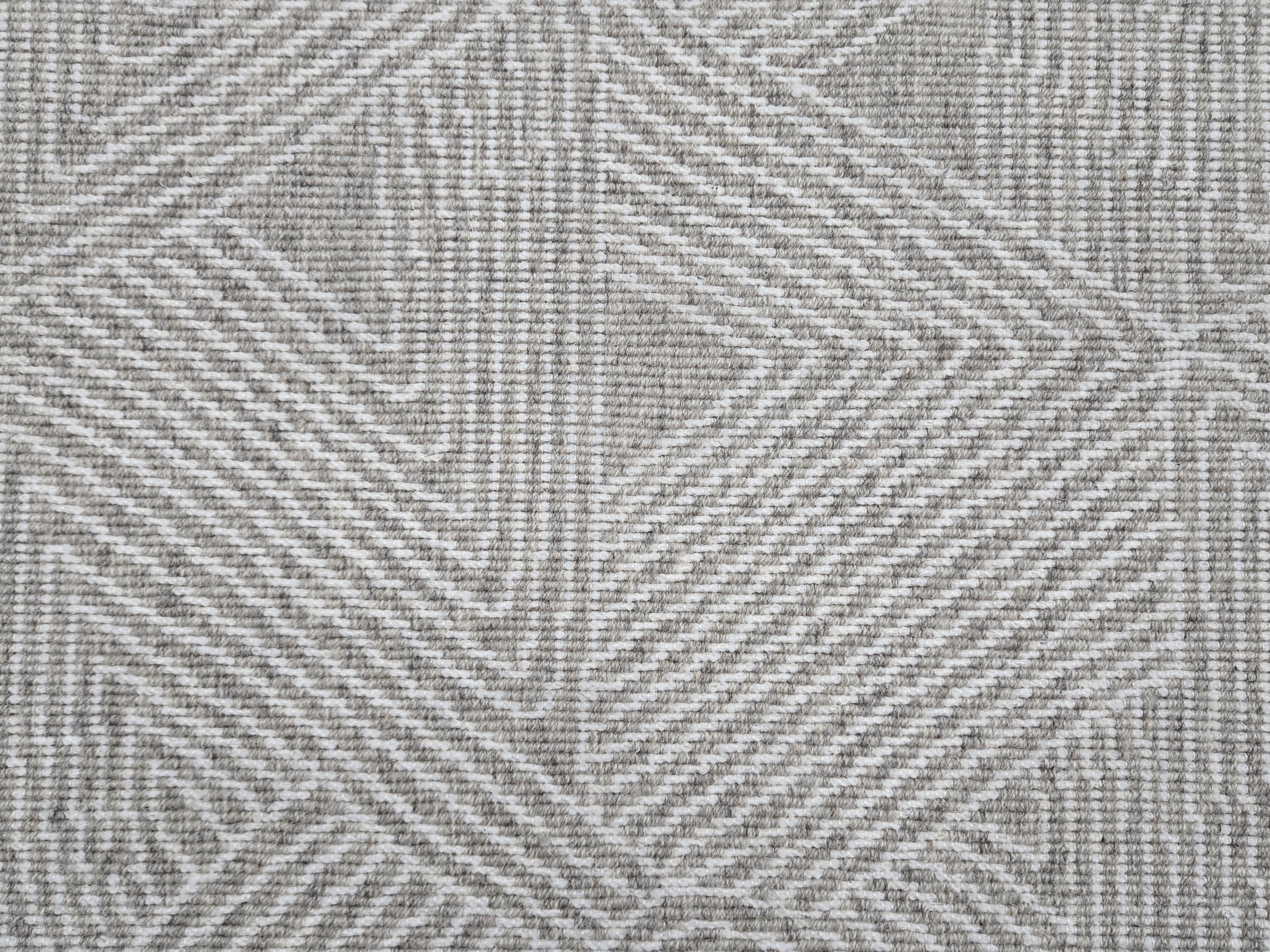 Broadloom carpet sample in a geometric linear pattern in cream on a grey field