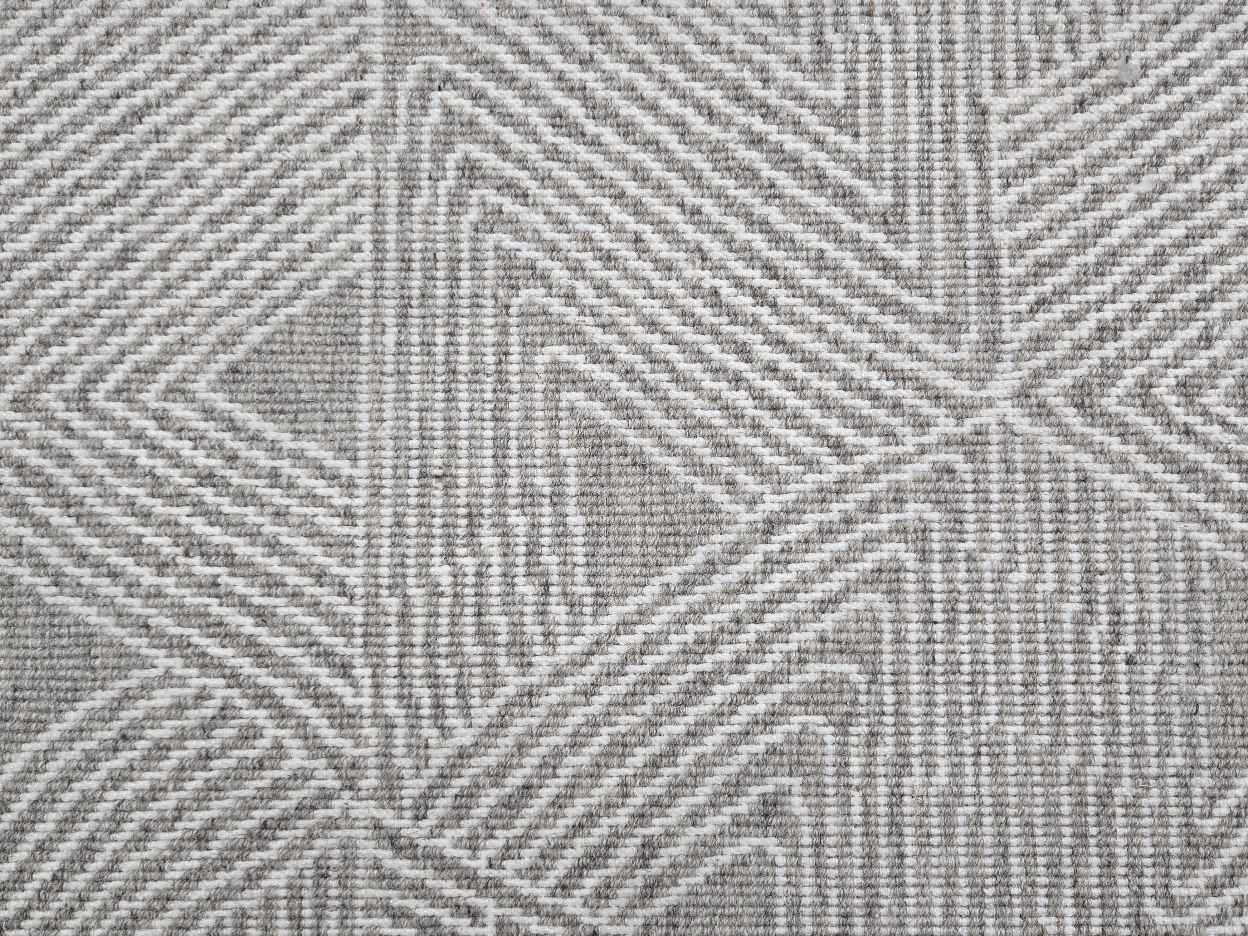 Broadloom carpet sample in a geometric linear pattern in cream on a light grey field.