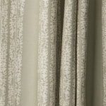 Draped printed fabric in a scrolling floral stripe pattern in cream on a light sage field.