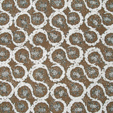 Detail of fabric in a meandering floral grid print in white and dark green on a brown field.